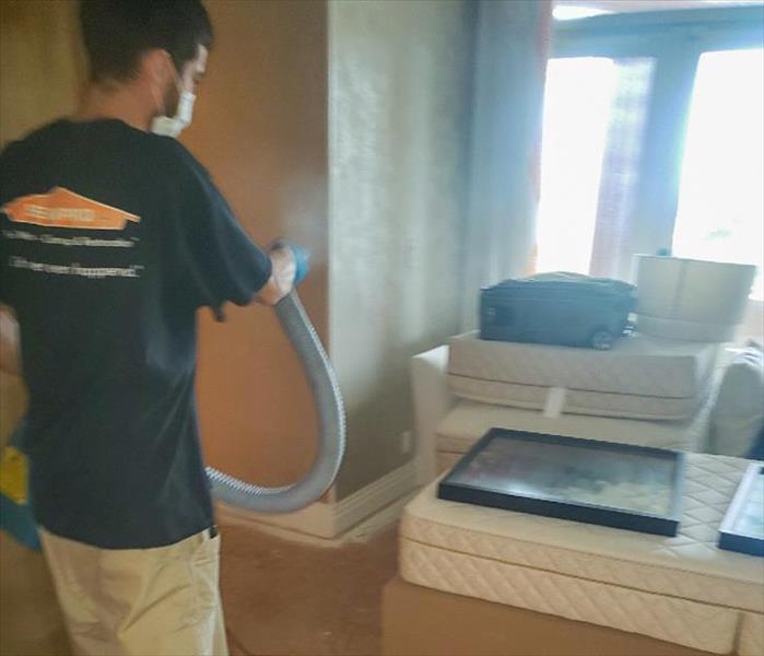 servpro employee using sprayer to disinfect room