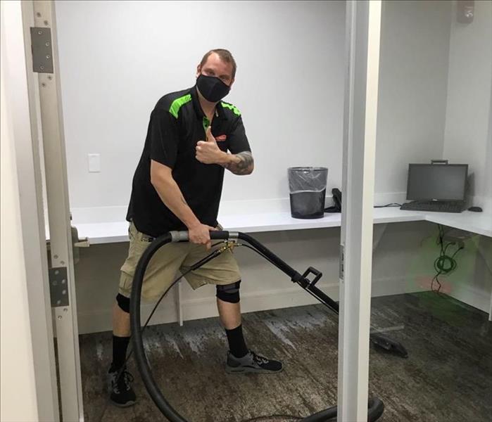 SERVPRO tech giving a thumbs up while cleaning a room in a Deerfield Beach, FL business